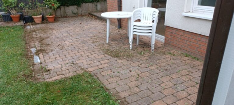 Verschmutzte Terrasse mit Unkraut und Laub vor der Reinigung - Gartenarbeit in Gehrden